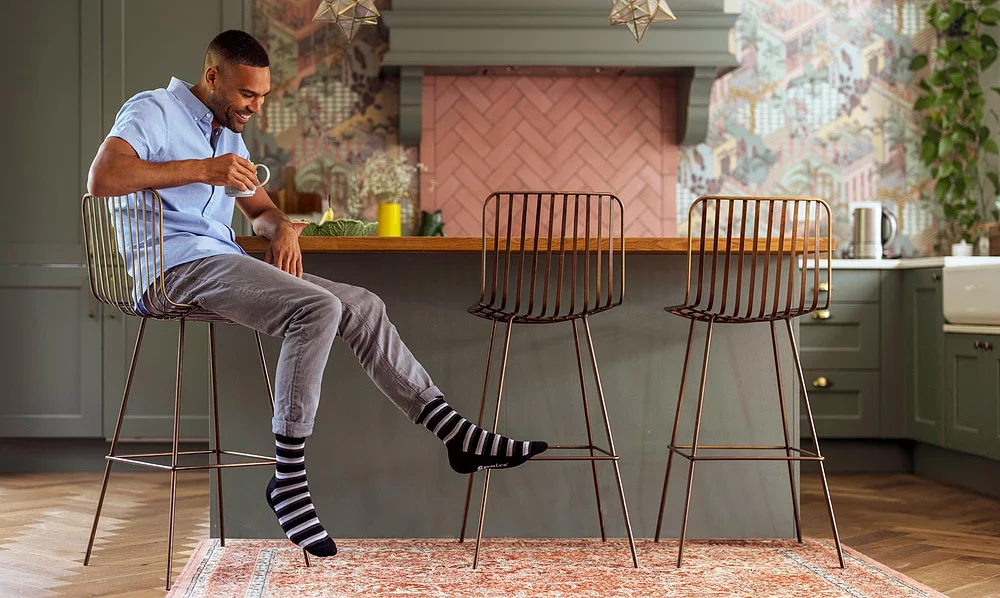 Men's striped bamboo socks in black and grey colours, worn casually indoors