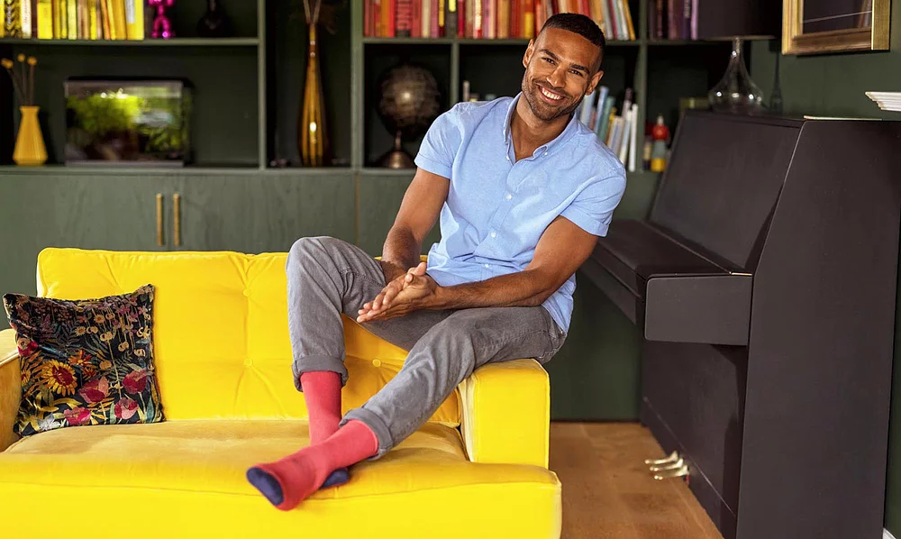 Man sitting on a sofa wearing teal and navy coloured striped cotton socks